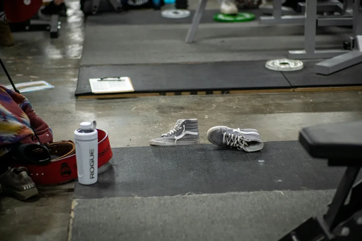 Gear, including a bottle of water, on a gym floor