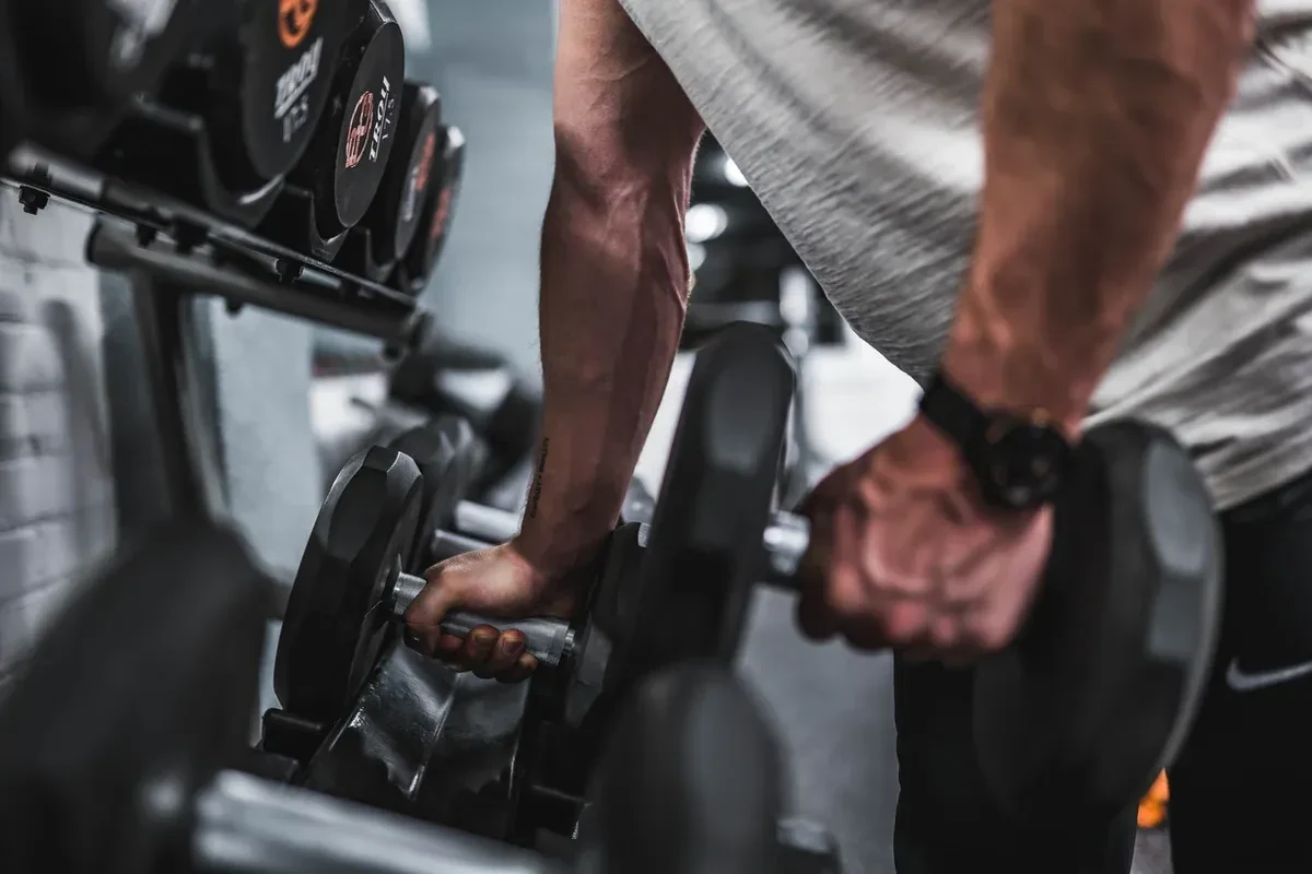 Close up of a male athlete lifting dumbbells off the rack in the gym