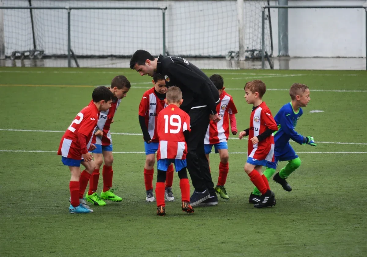 Youth coach teaching youth soccer players on a pitch