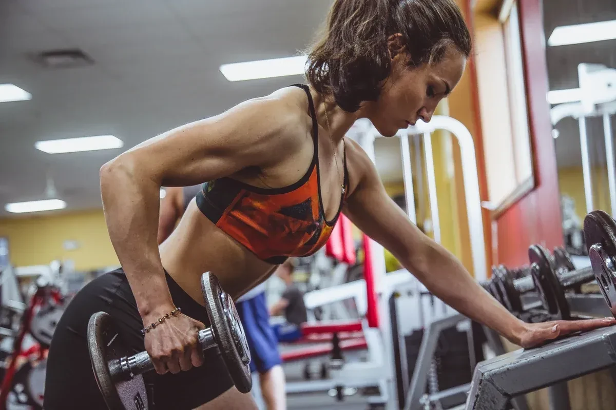 A woman exercising in a gym with a dumbbell 