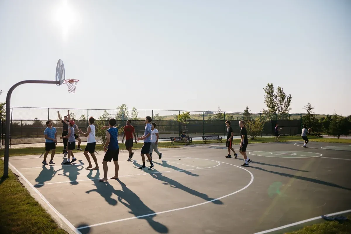Group playing basketball on a court in the summer
