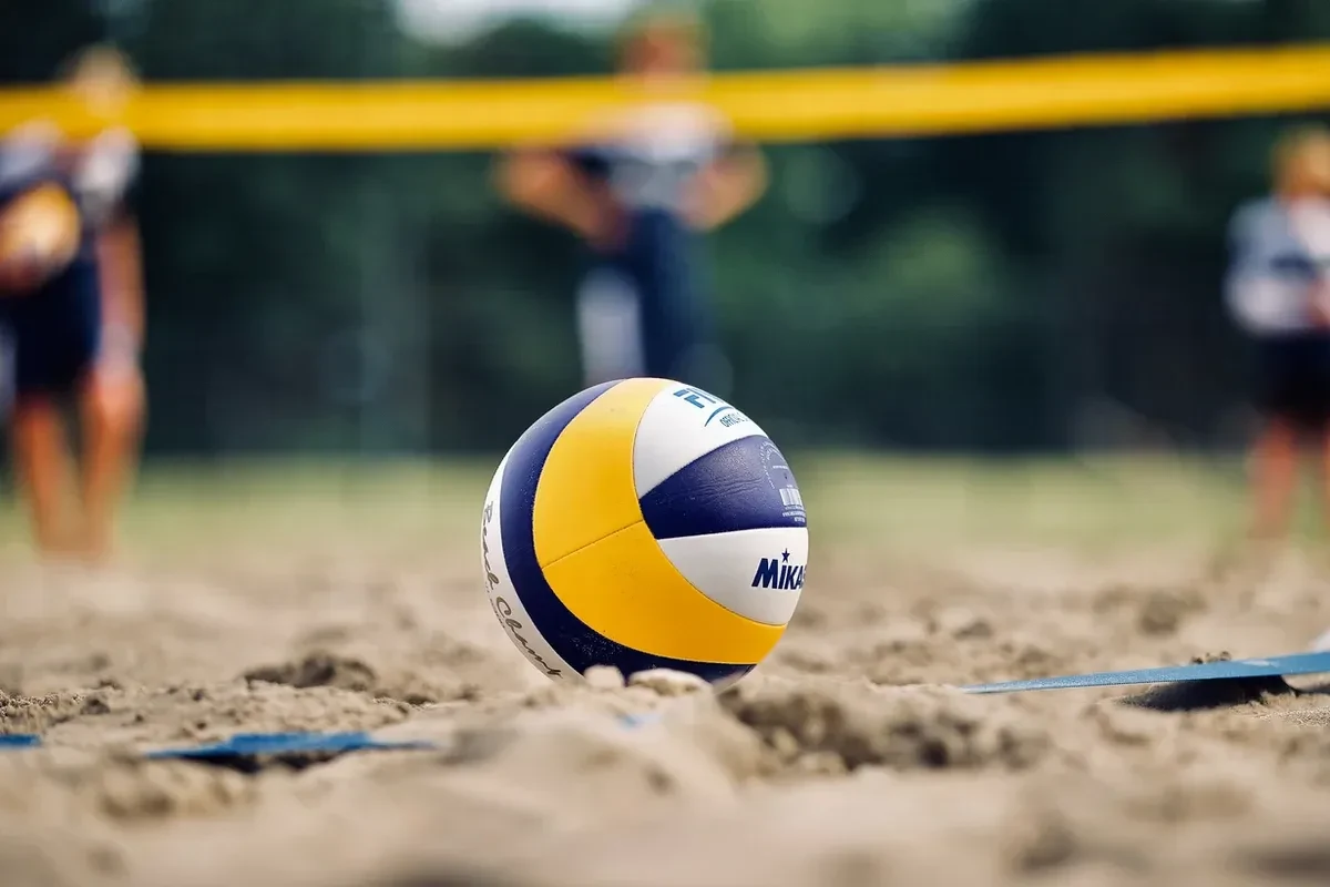 A volleyball on the sand of a beach volleyball game